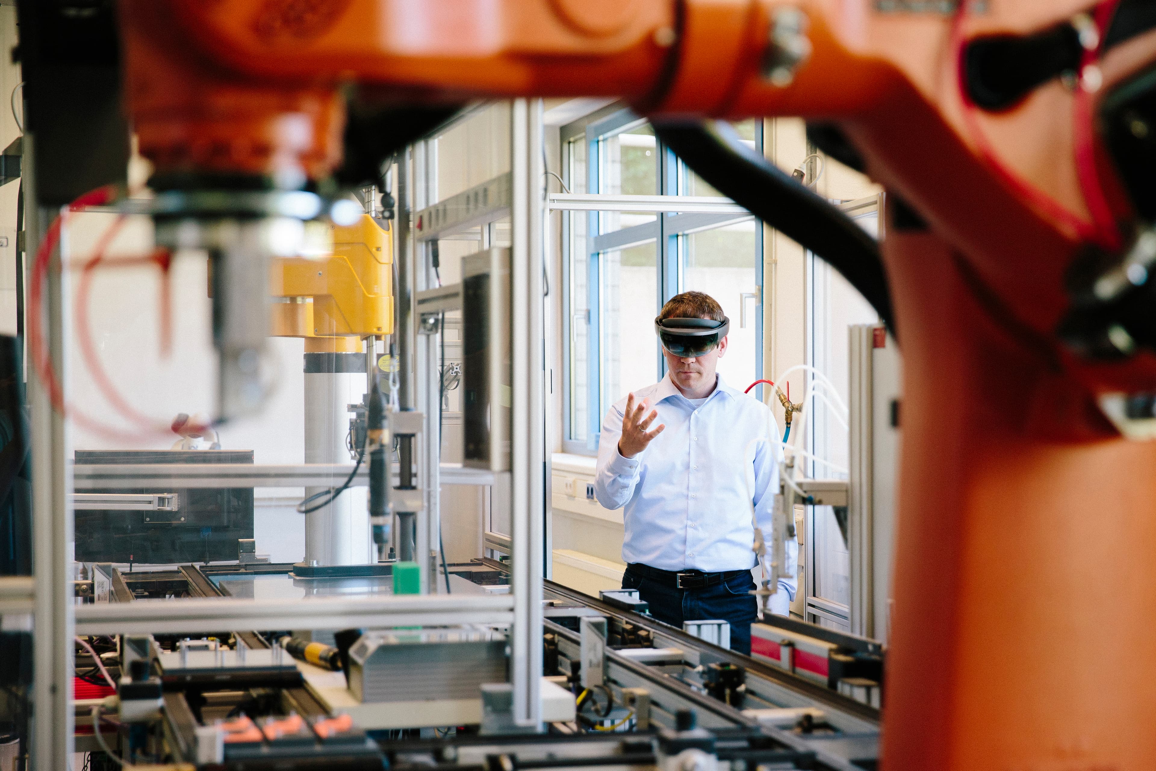 Engineer using an augmented reality headset alongside an industrial robotic arm