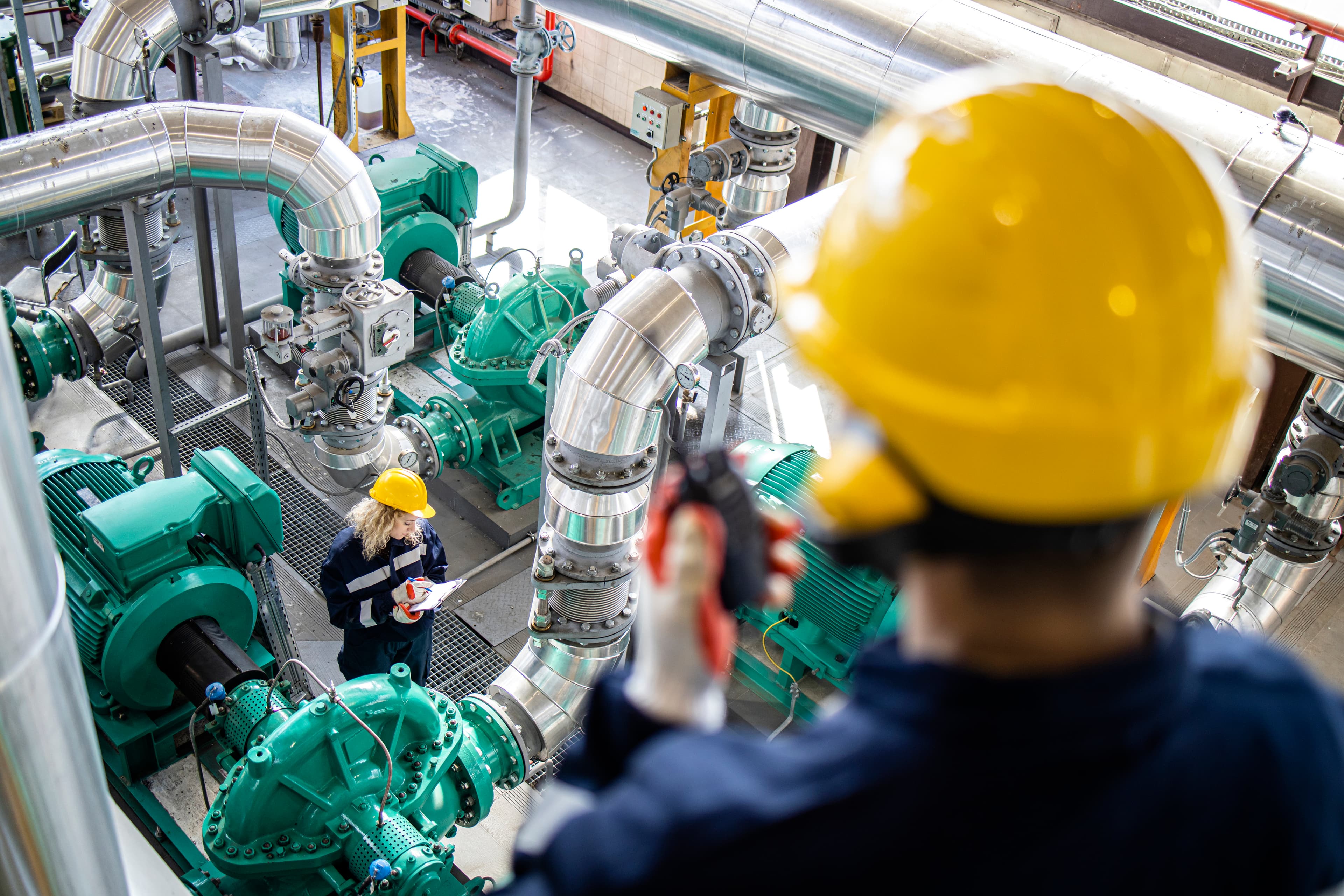 Maintenance technicians inspecting industrial pump and piping equipment